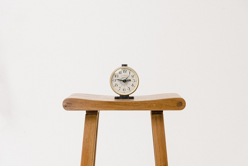 alarm clock sitting on wooden stool